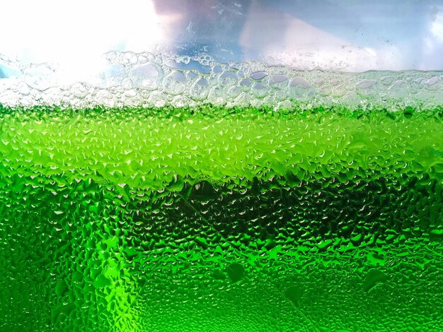 Full frame shot of green carbonated drink seen through glass