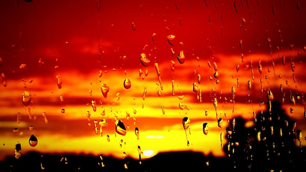Photo full frame shot of wet glass window against dramatic sky during sunset