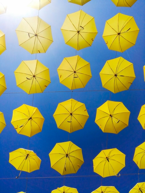 Foto fotografia completa di ombrelli gialli appesi contro un cielo blu limpido