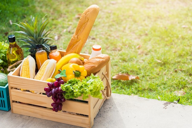 Full fresh vegetables and fruits in crate wood box, harvest organic food on the garden place of green leaves color background for copy space, Eat healthy concept