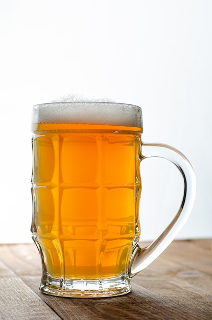 Full glass of blonde beer on white wooden backgroud