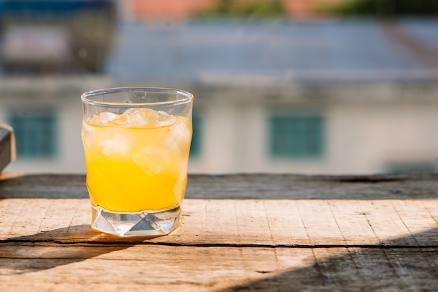 Full glass of orange juice close-up. Fresh orange juice on wooden table in out of focus unidentified restaurant in the morning in summer