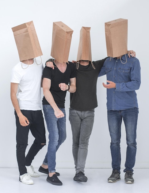 В полный рост группа мужчин с бумажными пакетами на головах. Фото с копией пространства.