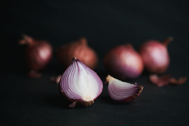 Full and half cut spanish onions on dark background.