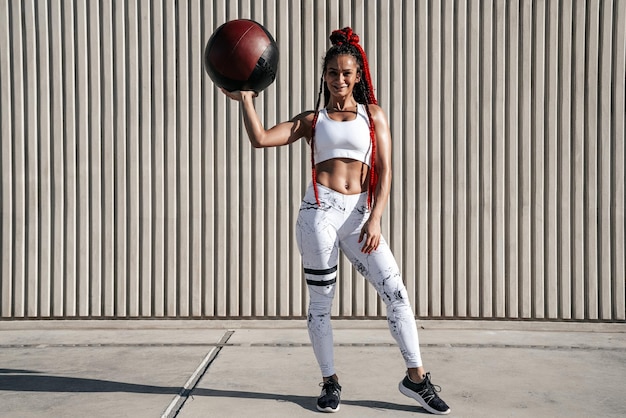 Full height Athletic woman with med ball Strength and motivationPhoto of sporty woman in fashionable sportswear