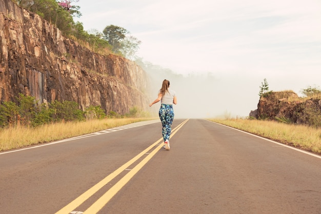 Full image of a young athlete running outdoors on an open road in the countryside