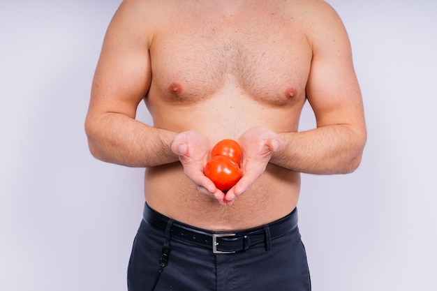 Полная изолированная студийная фотография молодого голого мужчины в нижнем белье и помидорах