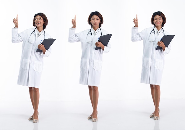 Full length 20s young Asian Doctor Woman wear stethoscope uniform coat pointing finger hand in air