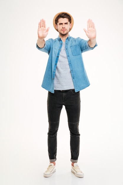 Full length of angry young man standing and showing stop gesture over white background