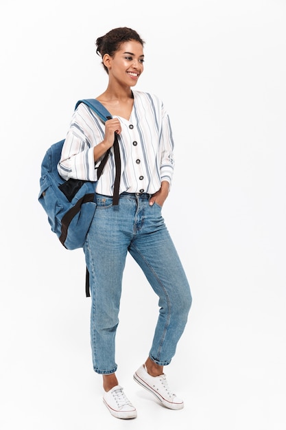 Full length of an attractive young african woman wearing casual clothes standing isolated over white wall, carrying backpack