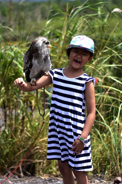 Photo full length of baby girl standing with an owl on her hand