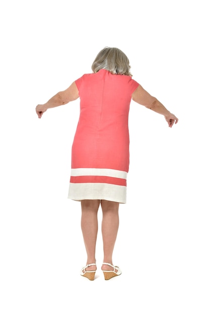 Full length back view portrait of senior woman in red dress pointing on white background
