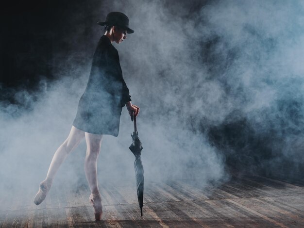 Foto lunghezza completa di una ballerina che tiene un ombrello sul palco