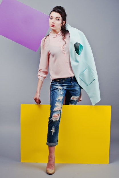 Full length of beautiful girl sitting, holding green blank advertising board , over gray background and yellow and violet banner