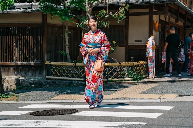 カラフルな着物をレンタルした後、着物屋から出て行く日本の伝統的なドレスを着た美しい観光客の全長。若い旅行者は日本旅行で日本文化を体験します。