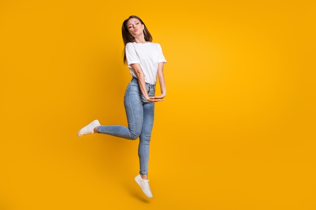 Full length body size photo of romantic girl sending air kiss with pouted lips isolated on vibrant yellow color background