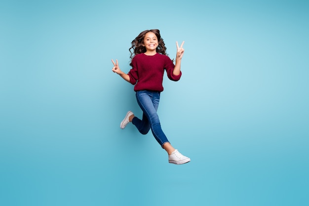 Full length body size turned photo of cheerful funny funky positive girl wearing denim footwear burgundy sweater showing you v-sign double isolated vivid color background