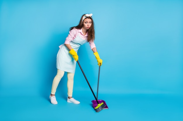 full length body size view of bored confused girl maid sweeping floor