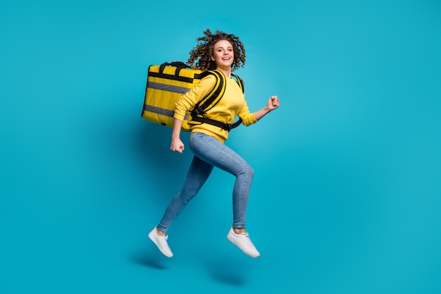 Full length body size view of girl jumping carrying package having fun isolated blue background