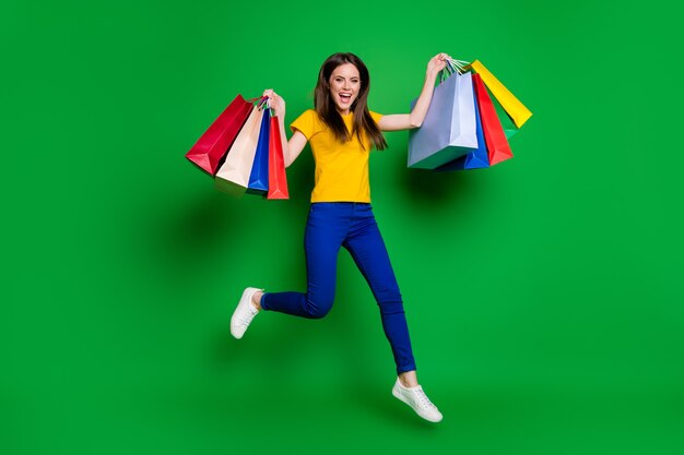 full length body size view of girl jumping carrying store packages