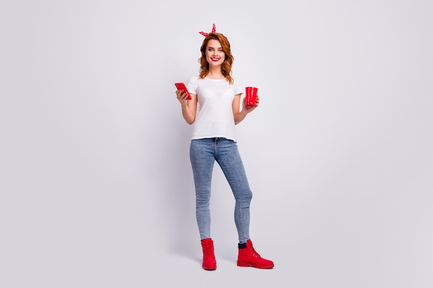 Full length body size view of her she nice attractive cheerful cheery girl holding in hand punch cup drinking beverage using 5g spending free time isolated over light white pastel color wall