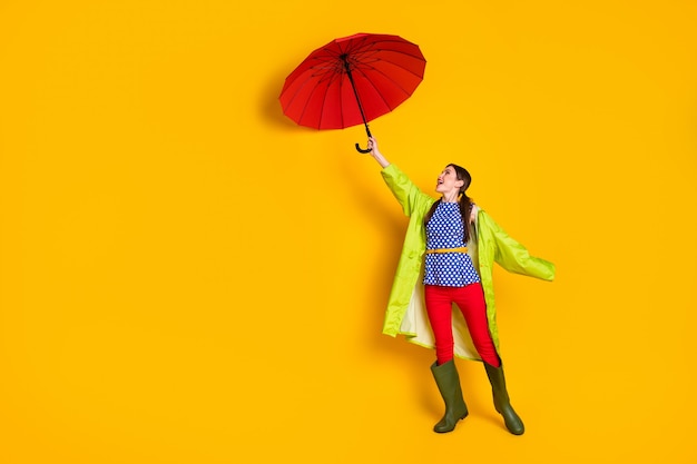 Full length body size view of her she nice attractive fashionable trendy cheerful cheery girl wearing green raincoat struggling hurricane isolated bright vivid shine vibrant yellow color background