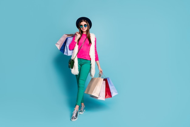 Full length body size view of nice attractive lovely fashionable cheerful cheery girl carrying new things bags isolated on bright vivid shine vibrant green blue turquoise color wall