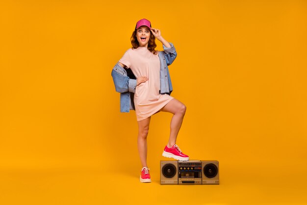 Full length body size view of nice attractive lovely girlish cool cheerful cheery girl putting leg on boombox having fun free time isolated on bright vivid shine vibrant yellow color background