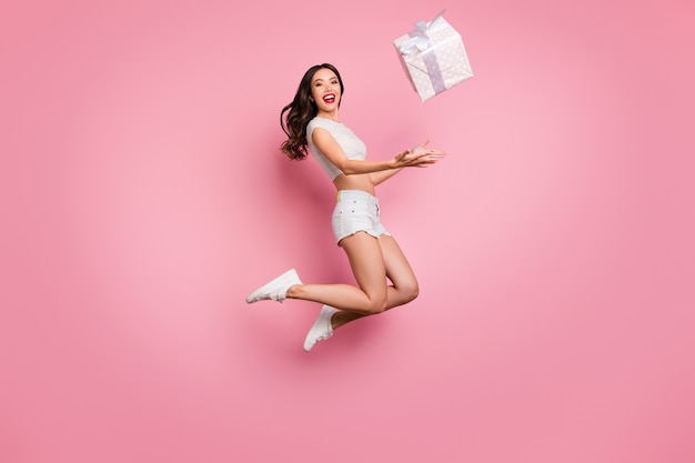 Full length body size view of nice attractive pretty lovely excited cheerful cheery wavy-haired girl jumping throwing gift box having fun isolated over pink pastel color wall