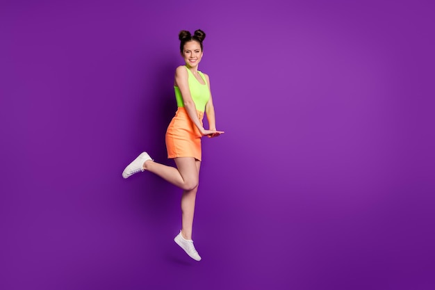 Full length body size view of slim fit cheerful girl jumping enjoying free spare time posing isolated over bright violet color background