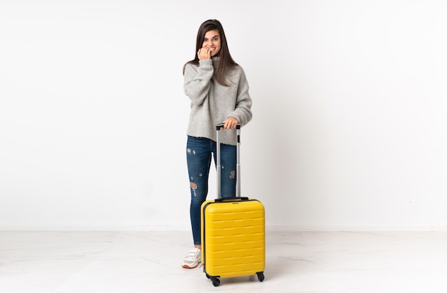 A full length body of a traveler woman with a suitcase over isolated white wall nervous and scared