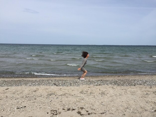 Full length of boy on beach against sky