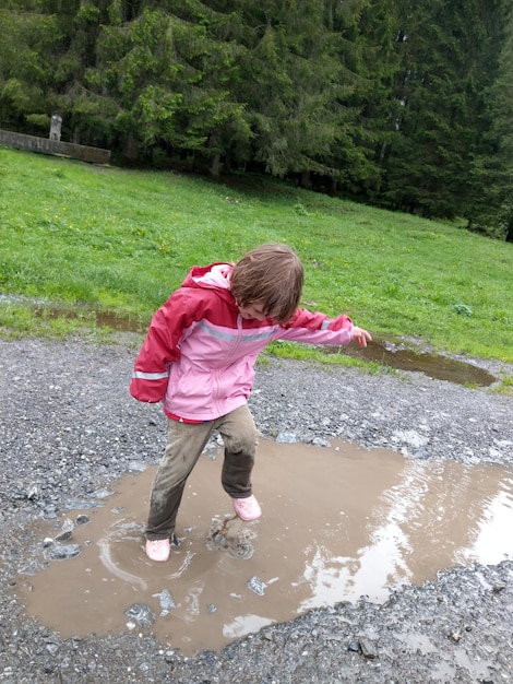 Photo full length of boy playing in puddle on field