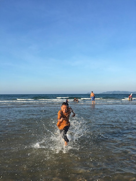 Full length of boy running on shore at beach