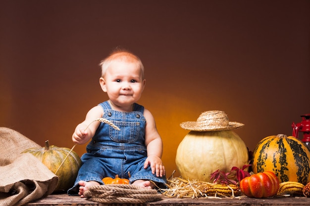 Full length of boy sitting against pumpkins