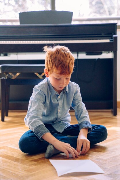 Photo full length of boy sitting on flooring