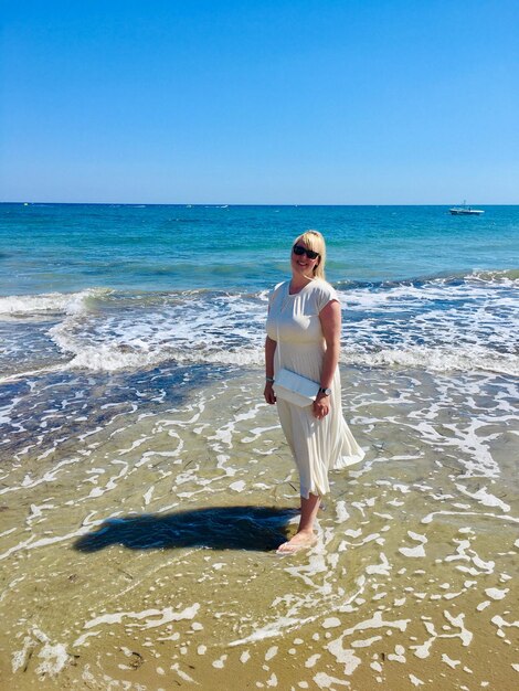 Full length of boy standing on beach against clear sky