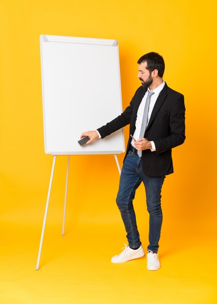 Full length  of businessman giving a presentation on white board over isolated yellow wall