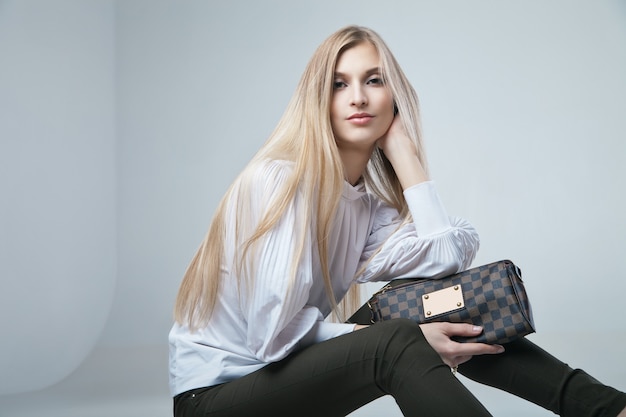 Full length casual young fashionable woman with a bag in light background