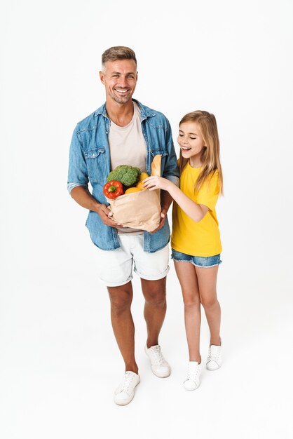 백인 가족 아버지와 딸의 전체 길이는 흰색으로 격리된 음식 가방을 들고 걷는 동안 웃고 있습니다.