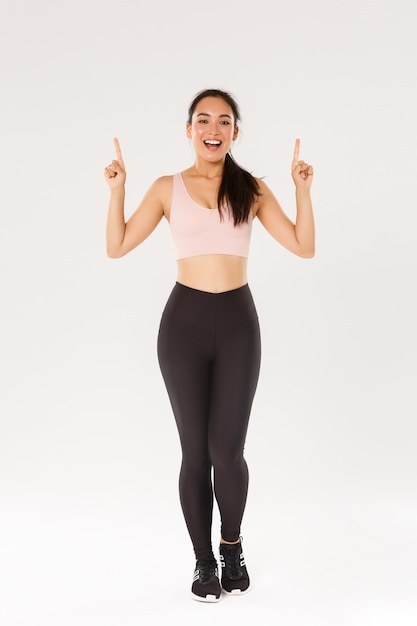 https://img.freepik.com/premium-photo/full-length-cheerful-smiling-asian-fitness-girl-female-athelte-sportswear-showing-advertisement-pointing-fingers-up-inviting-training-workout_1258-20599.jpg?size=626&ext=jpg