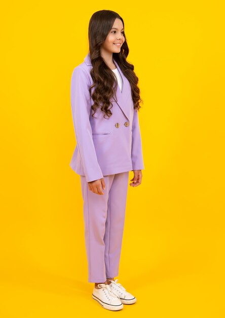 Full length of cheerful teenager child girl wearing comfy trendy fashion clothes isolated over yellow background Fashion kids suit Happy teenager positive and smiling emotions of teen girl