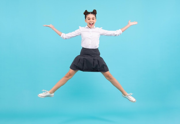 Full length cheerful teenager kid jump enjoy rejoice win isolated on blue background Small child girl in summer dress jumping Excited face Amazed expression cheerful and glad