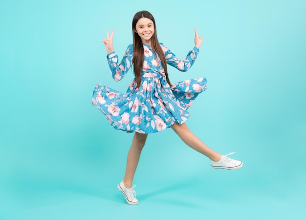 전체 길이 쾌활한 십대 아이 점프는 파란색 배경에 고립 된 기쁨 승리를 즐길 여름 드레스 점프에 작은 아이 소녀