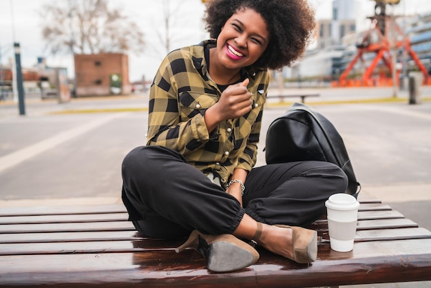 Photo full length of cheerful young woman sitting on table in city