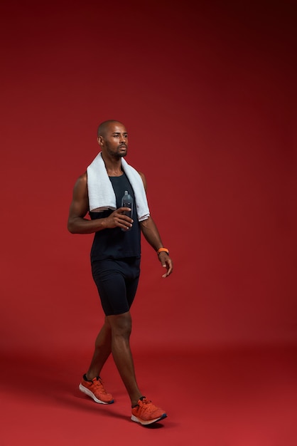 Full length of confident afro american man in sports clothing with towel on his shoulders