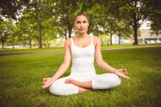 Full length of confident woman in lotus pose at park