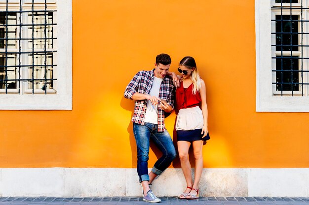 Full length of couple using phone while standing by house