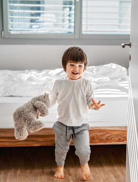 Full length of cute boy standing by bed at home