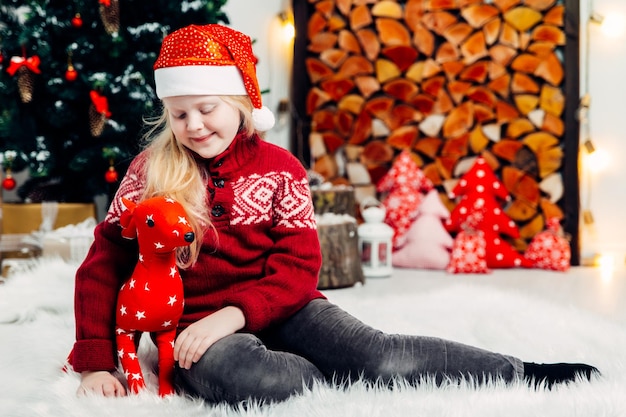 Photo full length of cute girl sitting with toy on carpet